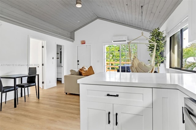 kitchen featuring light countertops, an AC wall unit, vaulted ceiling, and white cabinetry