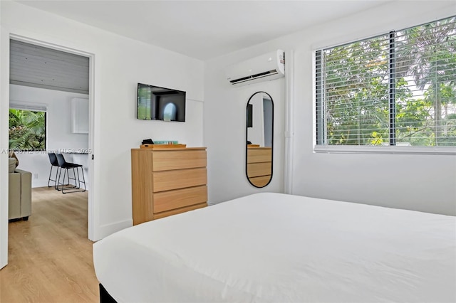 bedroom featuring a wall unit AC and light wood finished floors