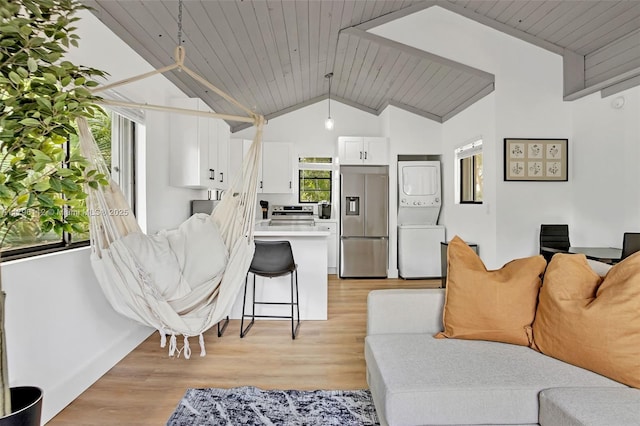 living area with wooden ceiling, stacked washer and clothes dryer, light wood finished floors, and high vaulted ceiling