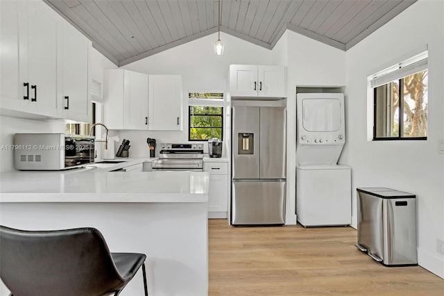 kitchen featuring wooden ceiling, a sink, light wood finished floors, appliances with stainless steel finishes, and stacked washer / drying machine