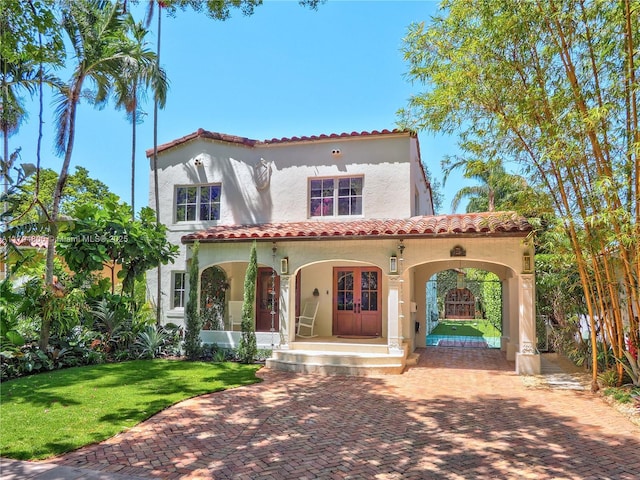1229 Sorolla Ave, Coral Gables, FL 33134 - mediterranean / spanish home featuring stucco siding, a tile roof, covered porch, and a front lawn