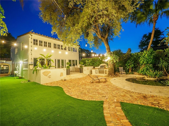 1229 Sorolla Ave, Coral Gables, FL 33134 - yard at twilight with exterior kitchen and a patio area
