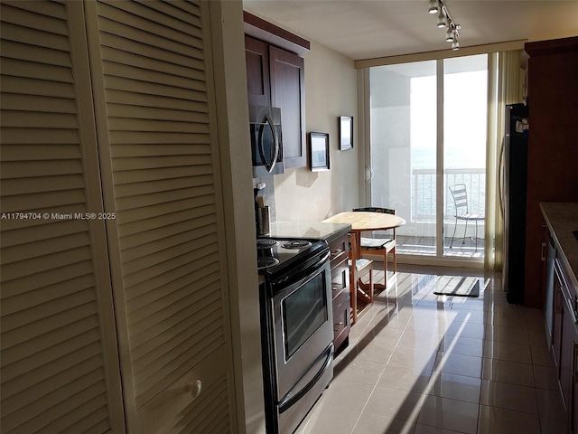 kitchen featuring track lighting, floor to ceiling windows, light tile patterned flooring, and stainless steel appliances