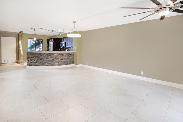 empty room with baseboards, a sink, ceiling fan, and track lighting