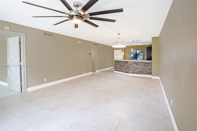 unfurnished living room with track lighting, baseboards, a ceiling fan, and visible vents