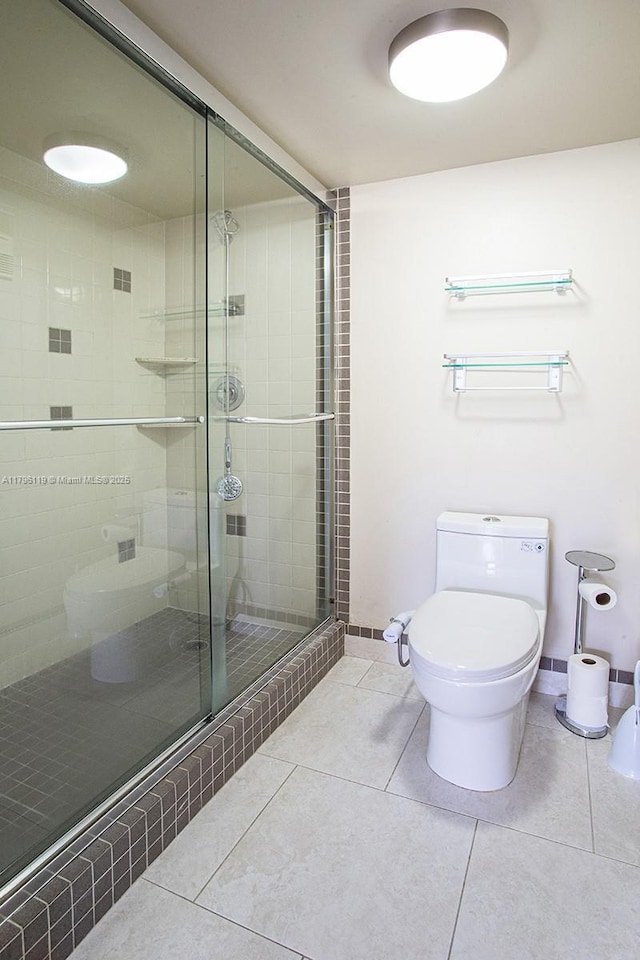 full bath featuring toilet, baseboards, tile patterned flooring, and a stall shower