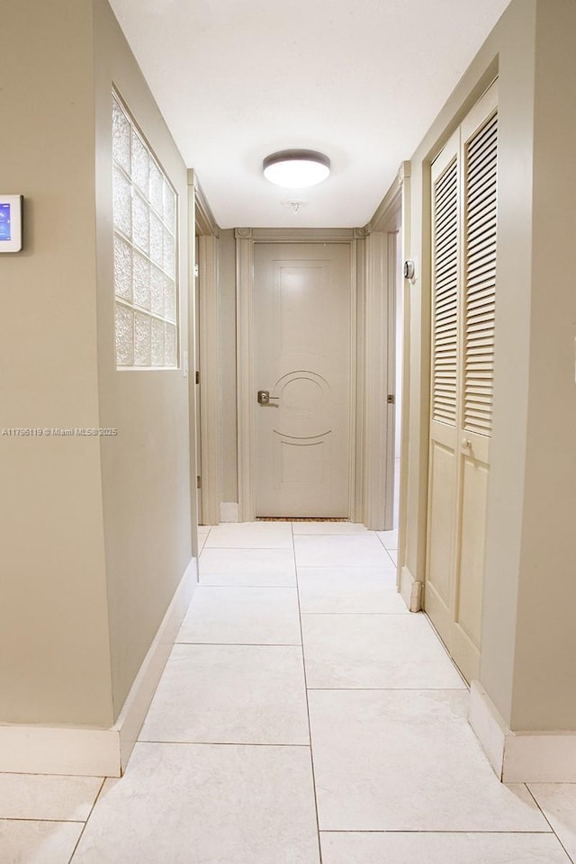 hallway featuring baseboards and light tile patterned floors