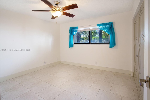 spare room featuring baseboards, ceiling fan, and light tile patterned flooring