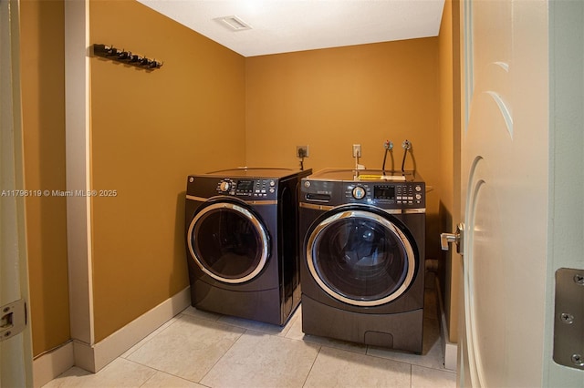 laundry area with laundry area, visible vents, baseboards, tile patterned floors, and separate washer and dryer