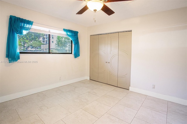 unfurnished bedroom with light tile patterned floors, baseboards, a ceiling fan, and a closet