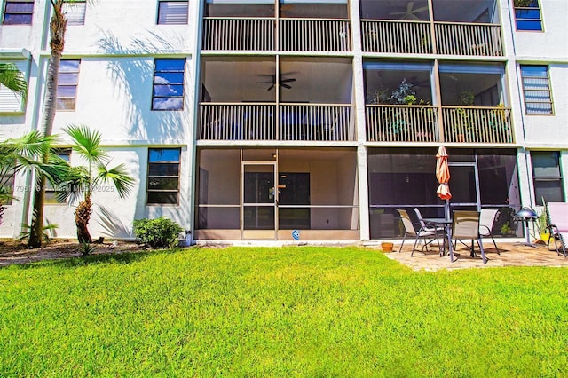 rear view of property with a ceiling fan, a patio, and a yard