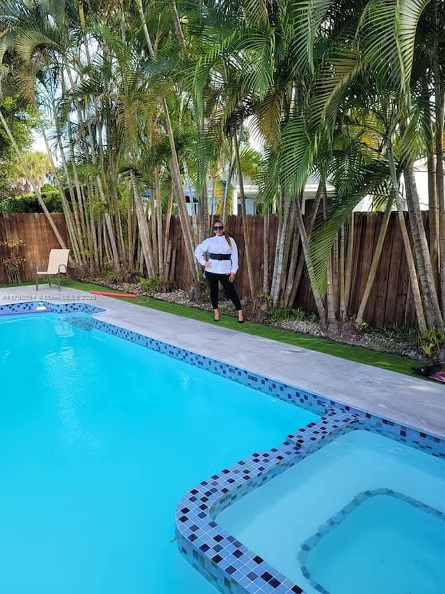 view of swimming pool featuring a fenced backyard and a pool with connected hot tub