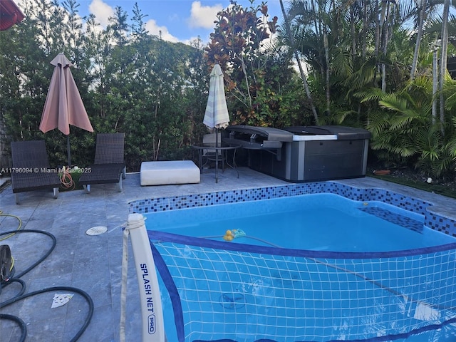 pool with a hot tub and a patio area