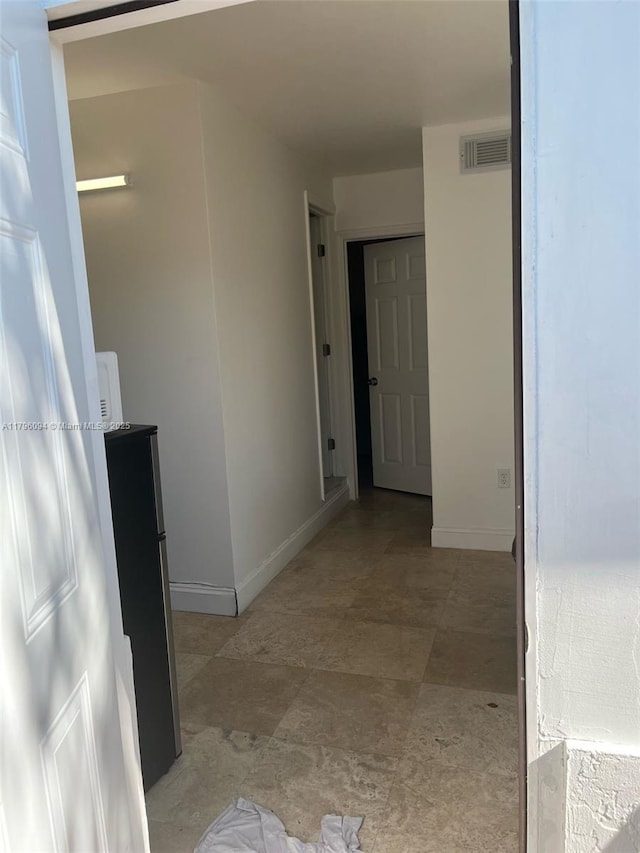 hall featuring visible vents and baseboards