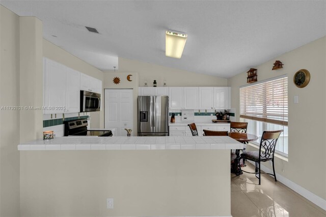 18271 SW 27th St, Miramar, FL 33029 - kitchen featuring stainless steel appliances, a peninsula, tile counters, tasteful backsplash, and white cabinetry