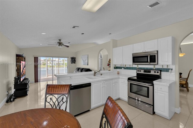 18271 SW 27th St, Miramar, FL 33029 - kitchen with appliances with stainless steel finishes, arched walkways, a sink, a peninsula, and white cabinetry