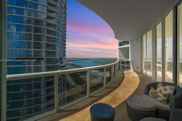balcony at dusk featuring a water view