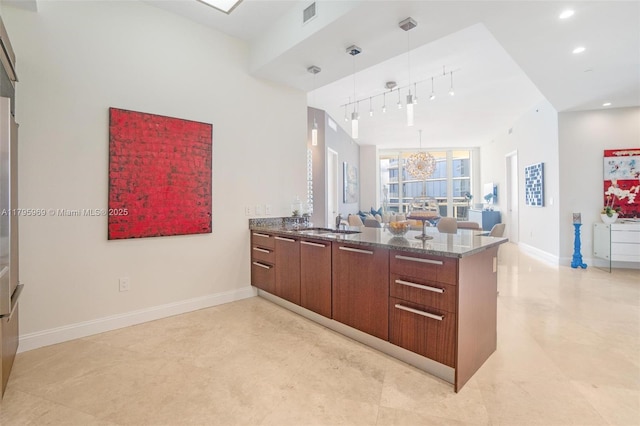 kitchen with visible vents, pendant lighting, a peninsula, baseboards, and dark stone counters