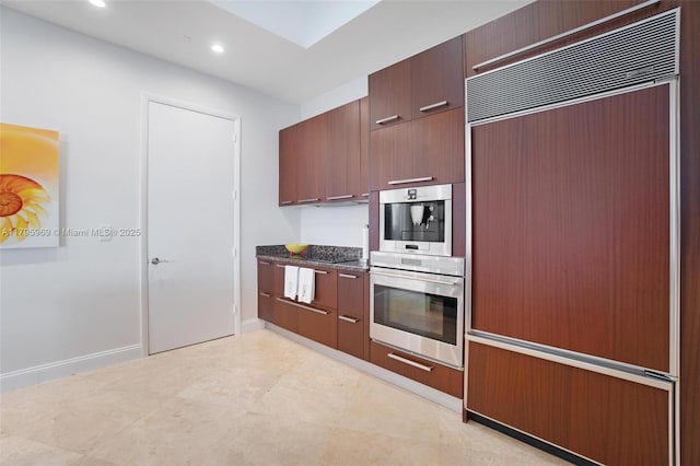 kitchen with modern cabinets, built in refrigerator, baseboards, dark stone countertops, and recessed lighting