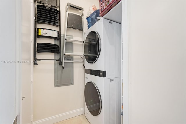 clothes washing area with baseboards, laundry area, and stacked washer / dryer