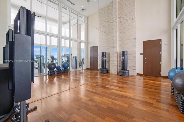 exercise room with wood finished floors and a towering ceiling