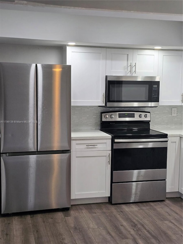 kitchen with light countertops, appliances with stainless steel finishes, white cabinets, and backsplash