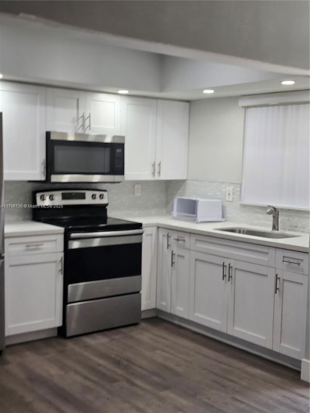 kitchen with a sink, appliances with stainless steel finishes, backsplash, and white cabinets