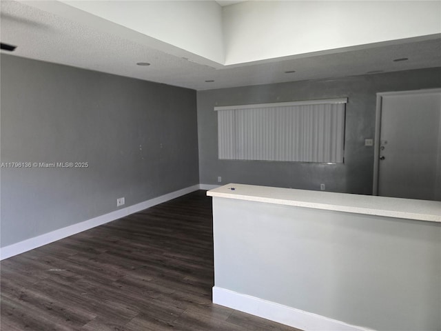 spare room with dark wood-type flooring and baseboards