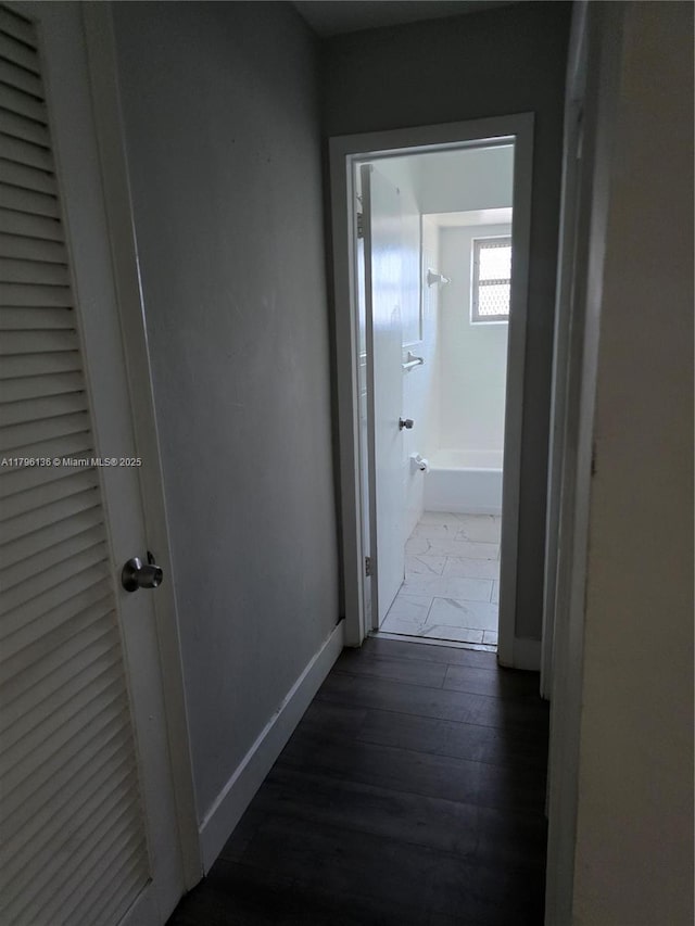 hallway featuring baseboards and dark wood-style flooring
