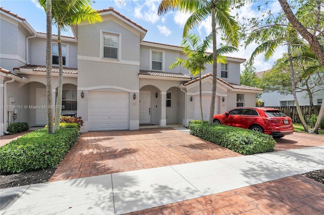 view of front of home featuring a garage, decorative driveway, stucco siding, and a tiled roof