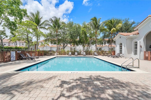 pool featuring fence, a patio, and a residential view