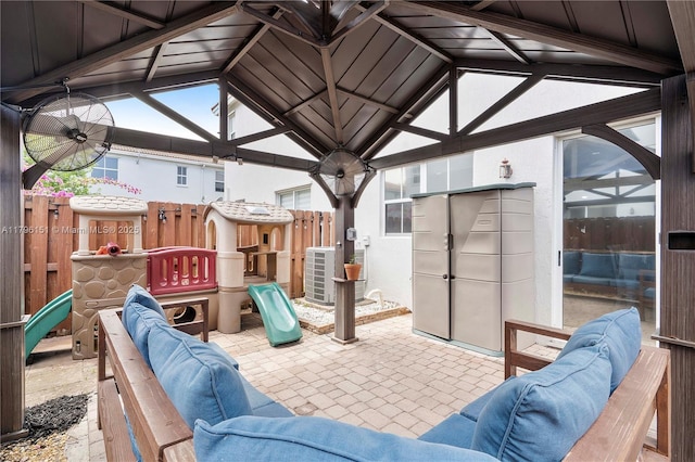 view of patio featuring fence, a gazebo, outdoor lounge area, central AC unit, and a playground