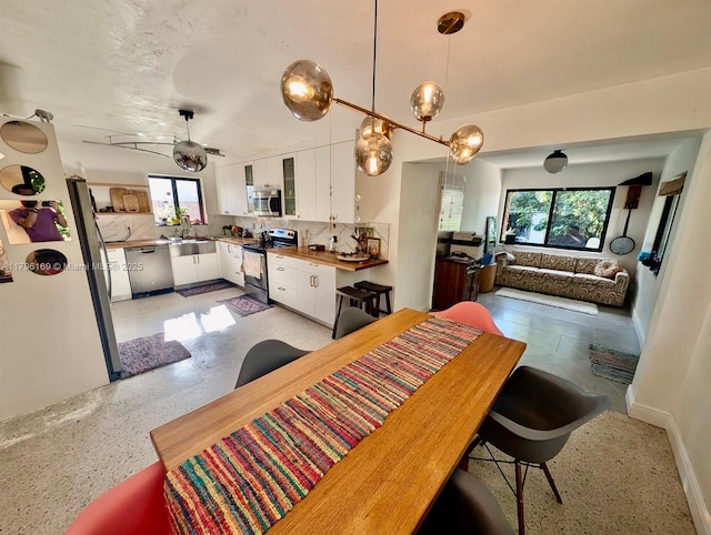 dining space featuring plenty of natural light, baseboards, and light speckled floor