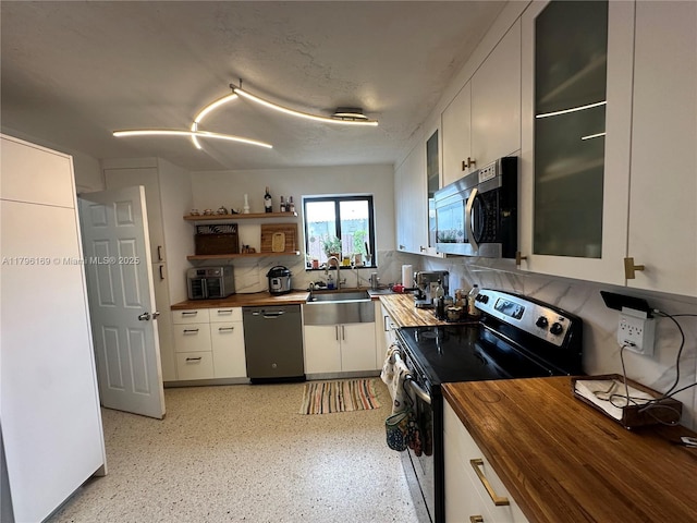 kitchen featuring butcher block counters, white cabinetry, a sink, backsplash, and stainless steel appliances