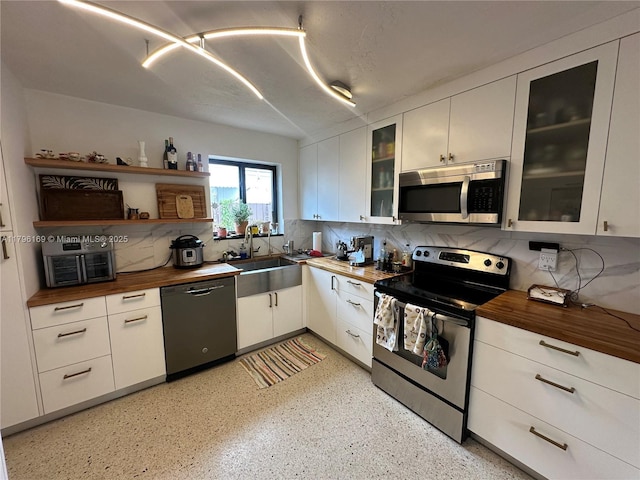 kitchen with butcher block countertops, a sink, tasteful backsplash, and stainless steel appliances