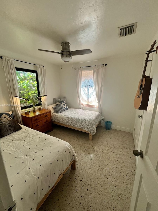 bedroom with baseboards, multiple windows, a ceiling fan, and visible vents