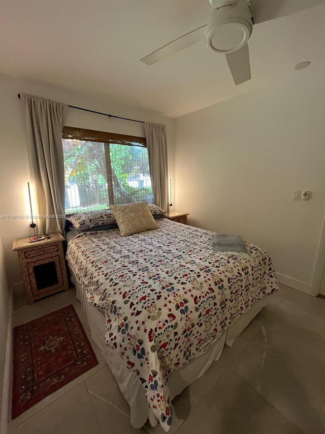 tiled bedroom with ceiling fan and baseboards