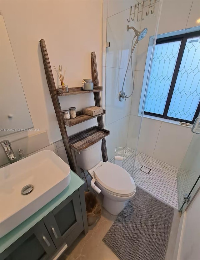 full bathroom with vanity, a tile shower, and toilet