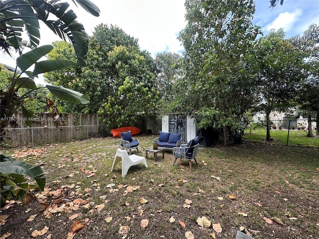 view of yard featuring an outdoor structure, a fenced backyard, and an outdoor living space