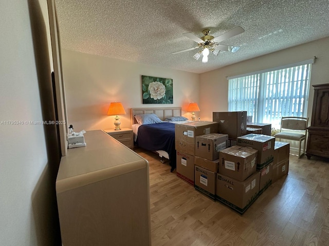 bedroom with a ceiling fan, a textured ceiling, and light wood-type flooring