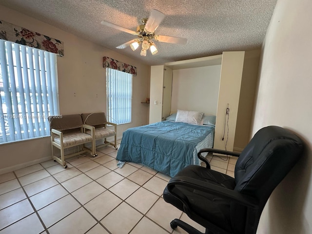 bedroom featuring light tile patterned flooring, a textured ceiling, a ceiling fan, and baseboards
