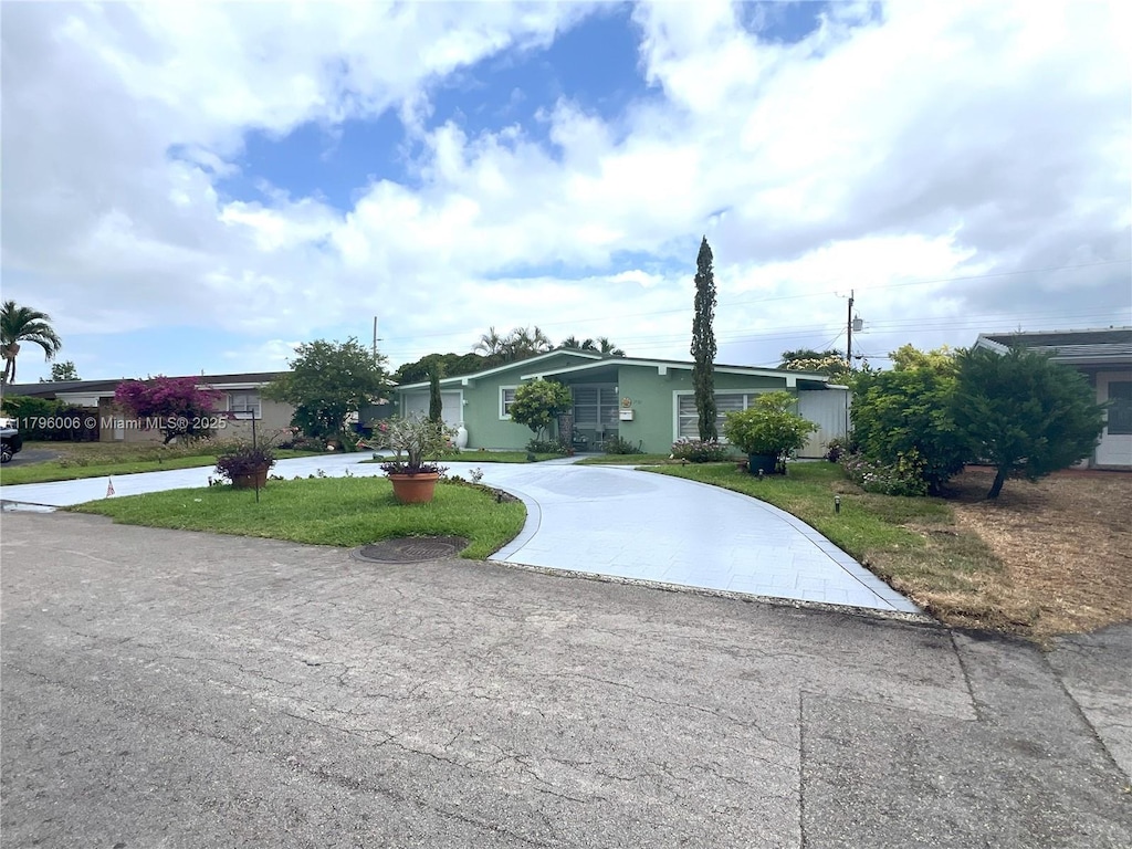 view of front of property featuring curved driveway, stucco siding, and a front yard