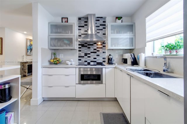 7691 NW 15th Ct, Pembroke Pines, FL 33024 - kitchen featuring stainless steel oven, wall chimney range hood, a sink, backsplash, and light countertops