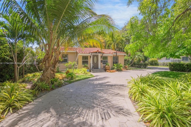 mediterranean / spanish-style house with driveway, a tile roof, and stucco siding