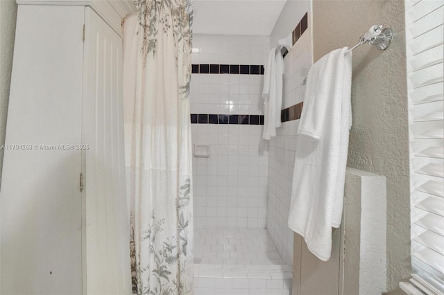 full bathroom featuring a textured wall and a stall shower