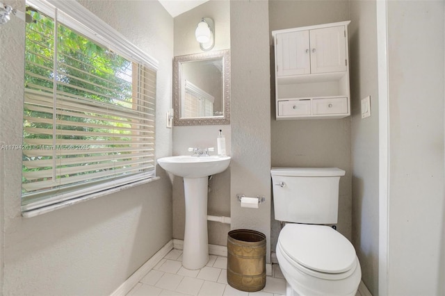 half bathroom with toilet, baseboards, a textured wall, and tile patterned flooring