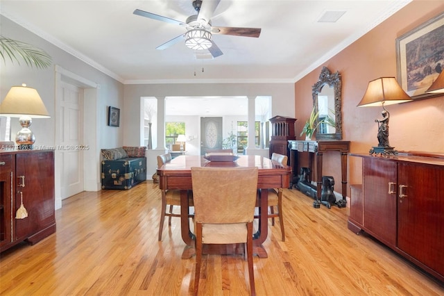 dining room featuring visible vents, ornamental molding, light wood-style floors, ceiling fan, and ornate columns
