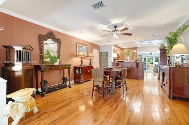 dining room with visible vents, ornamental molding, light wood-style floors, and ceiling fan