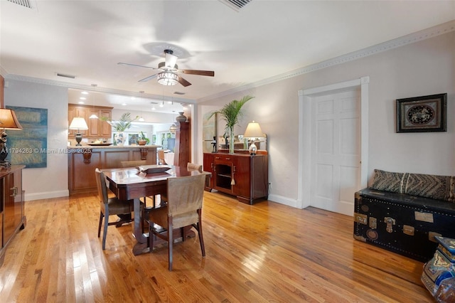 dining space featuring ceiling fan, visible vents, crown molding, light wood-type flooring, and baseboards