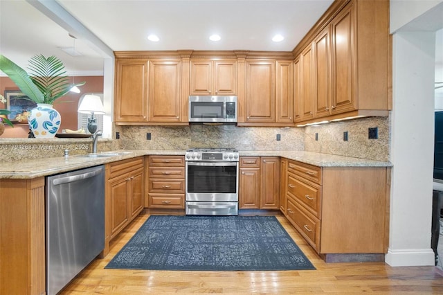 kitchen with light wood-style floors, light stone counters, a sink, backsplash, and stainless steel appliances